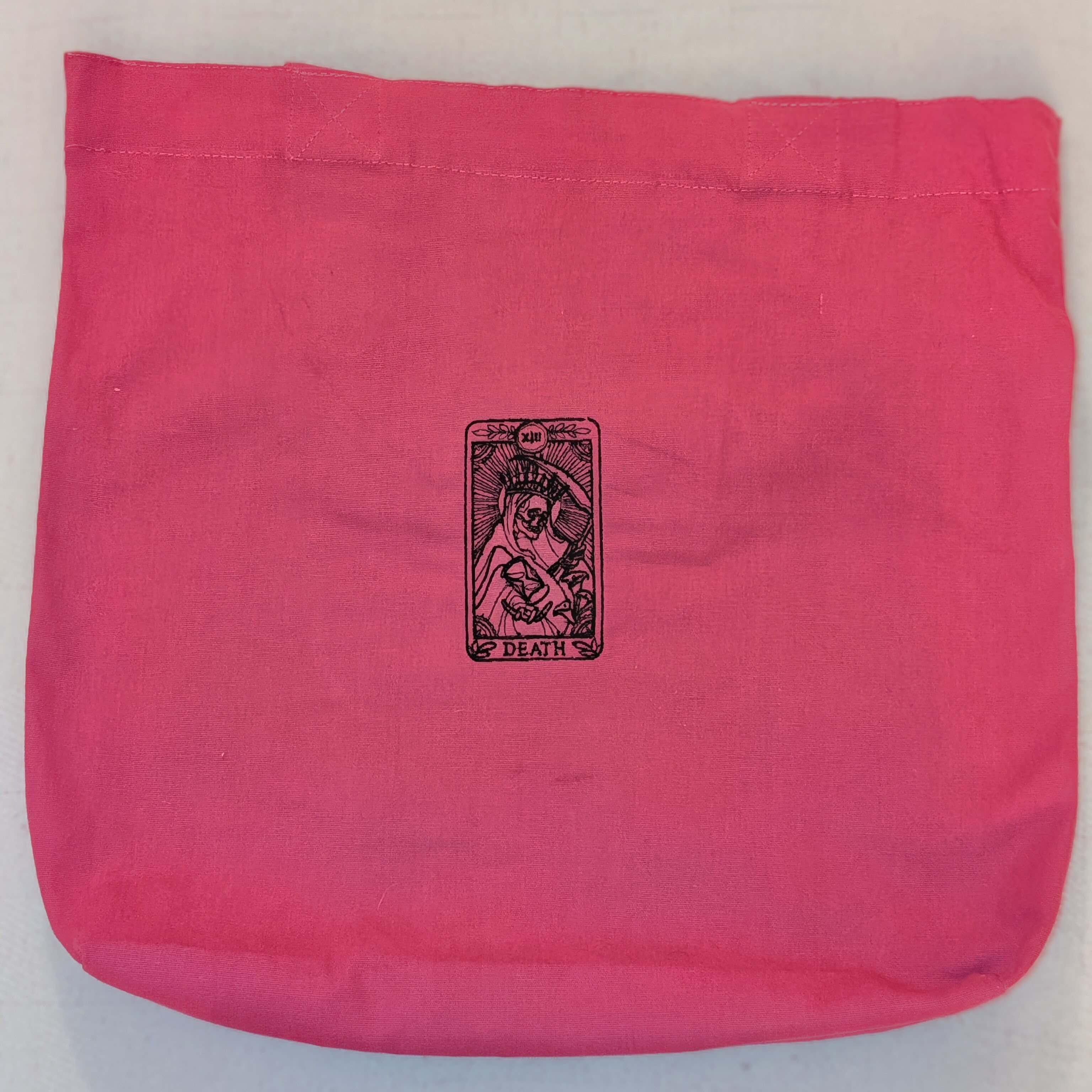 Pink fabric bag with a detailed black threadwork design of the Death tarot card, featuring a skeletal figure with a scythe.